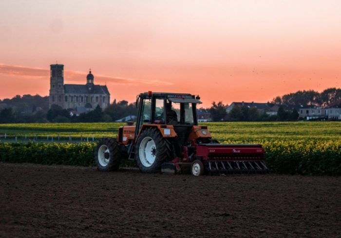 Tractor in farm field at sunset